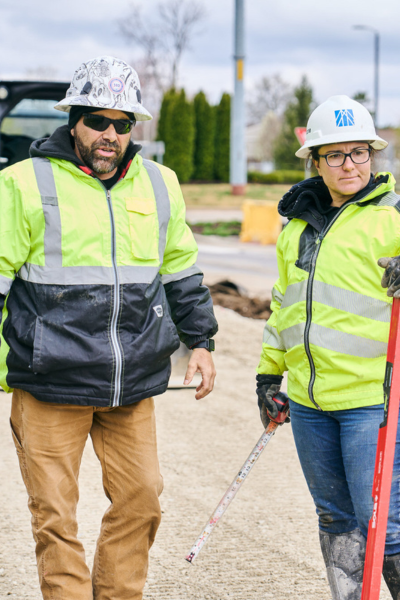 Man and woman standing side-by-side surveying a construction site